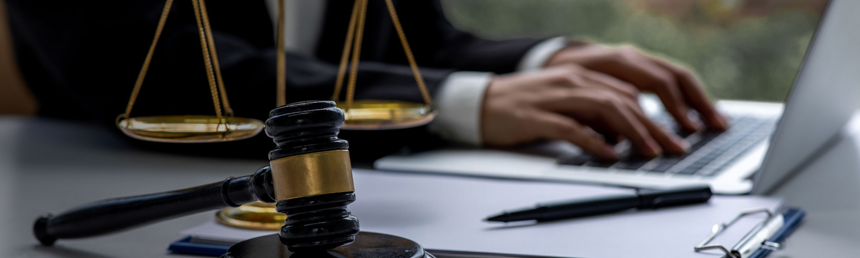 Man writing on laptop computer at a desk with scales and gavel