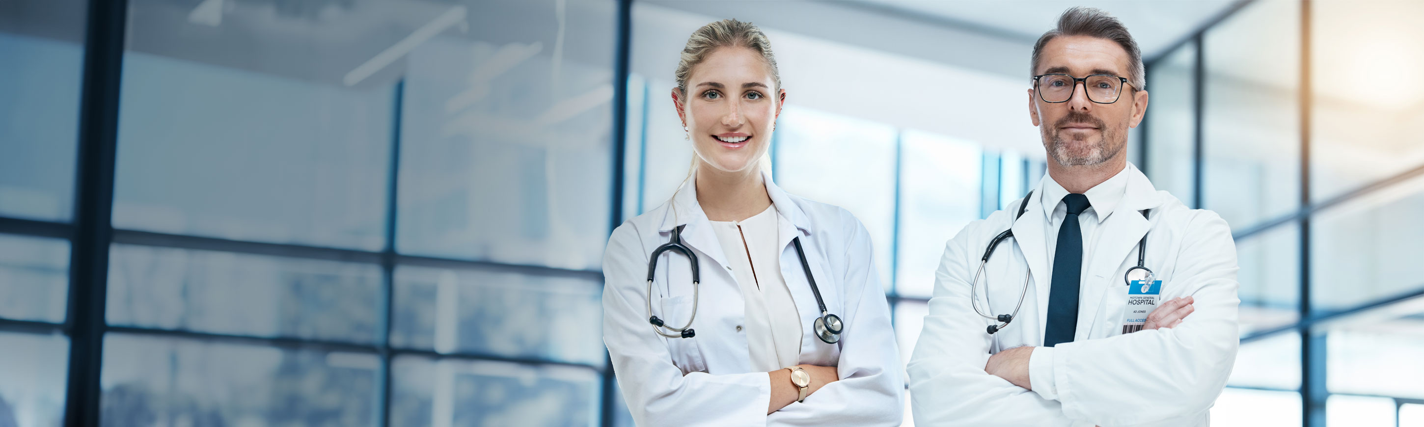 Two doctors, a woman and a man, with stethoscopes standing in a medical office