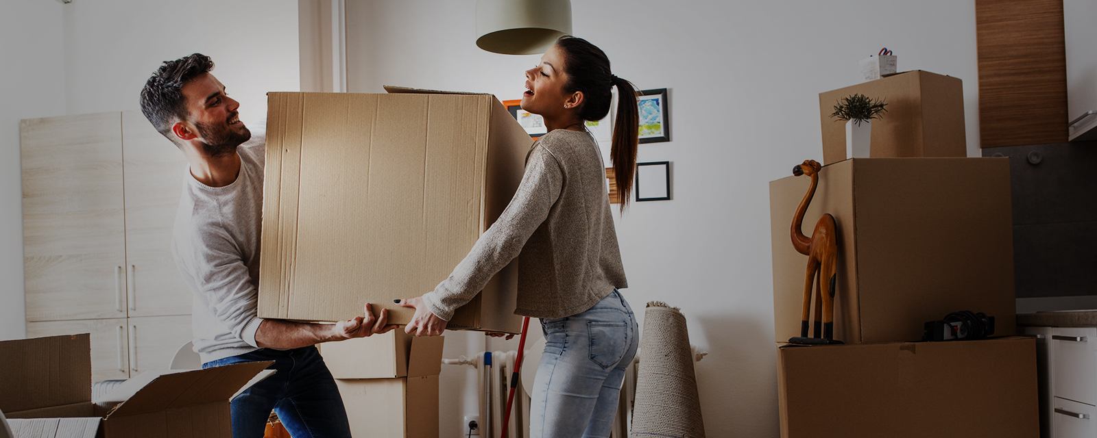 Young man and young woman carrying a box as they move into their new home or apartment