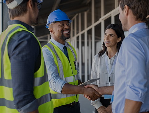 three guys and a woman at a construction site shaking hands