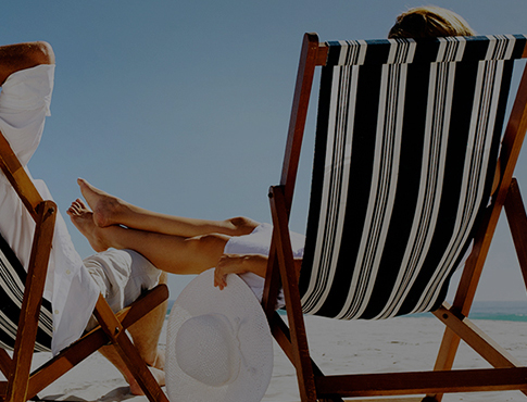 woman sitting on beach chair relaxing by the beach holding a white hat