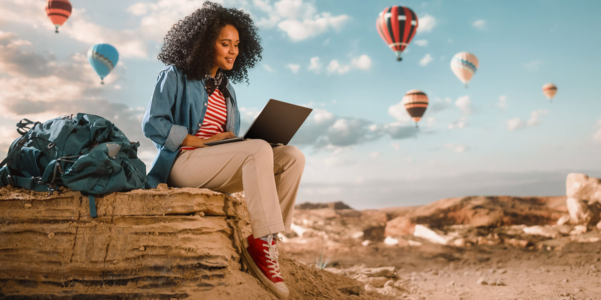 Woman looking at laptop with sky and air balloons in background