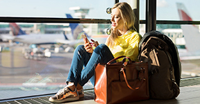 A young woman looking at her phone while waiting at the airport