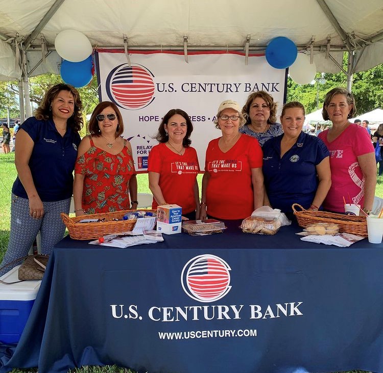 U.S. Century Bank employees standing behind a table
