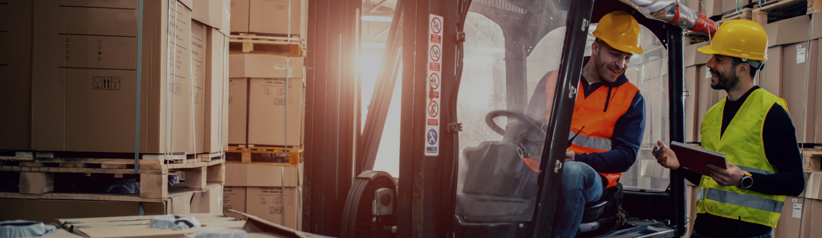 Two construction workers on a forklift discussing work plan.