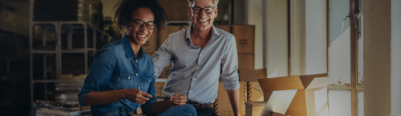 young woman and man at their business surrounded by boxes