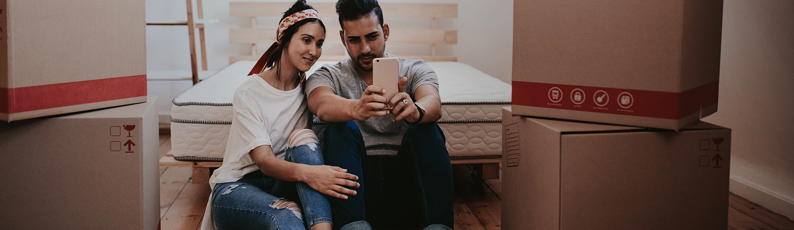 young couple holding phone as they move into new home