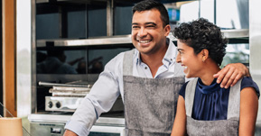 Man and woman smiling in restaurant kitchen