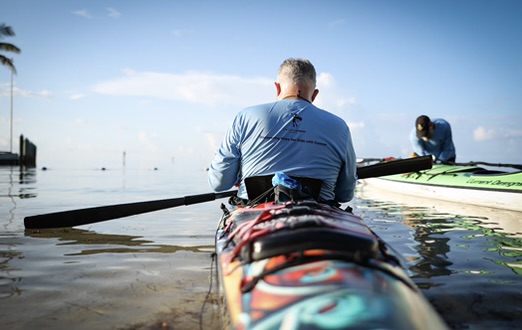 Back view picture of man kayaking.