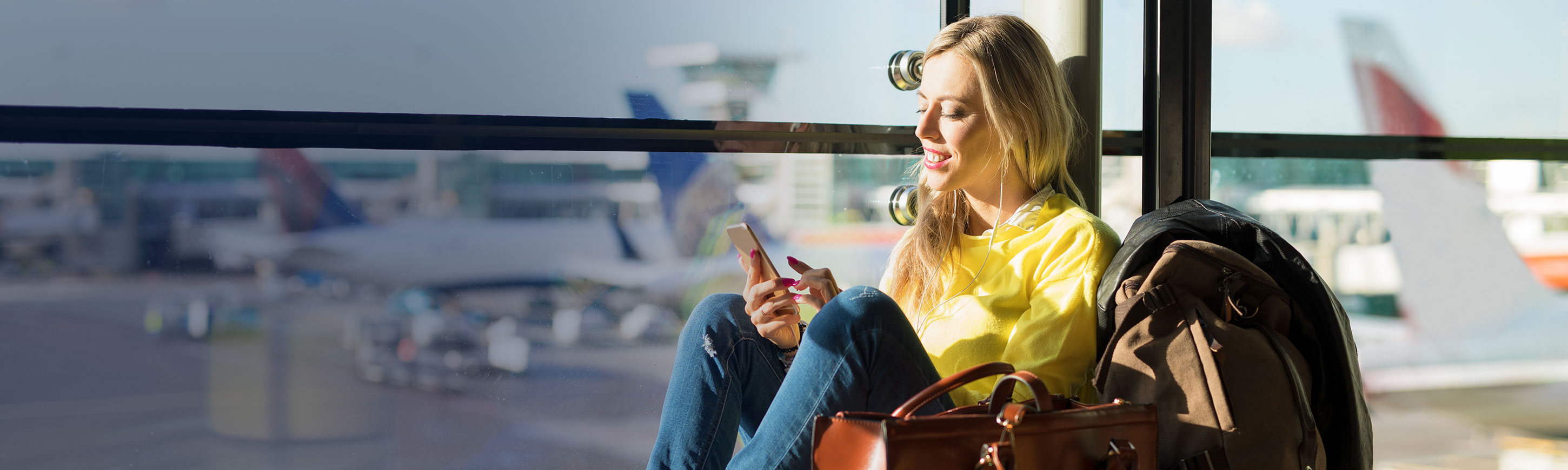 A young woman looking at her phone while waiting at the airport